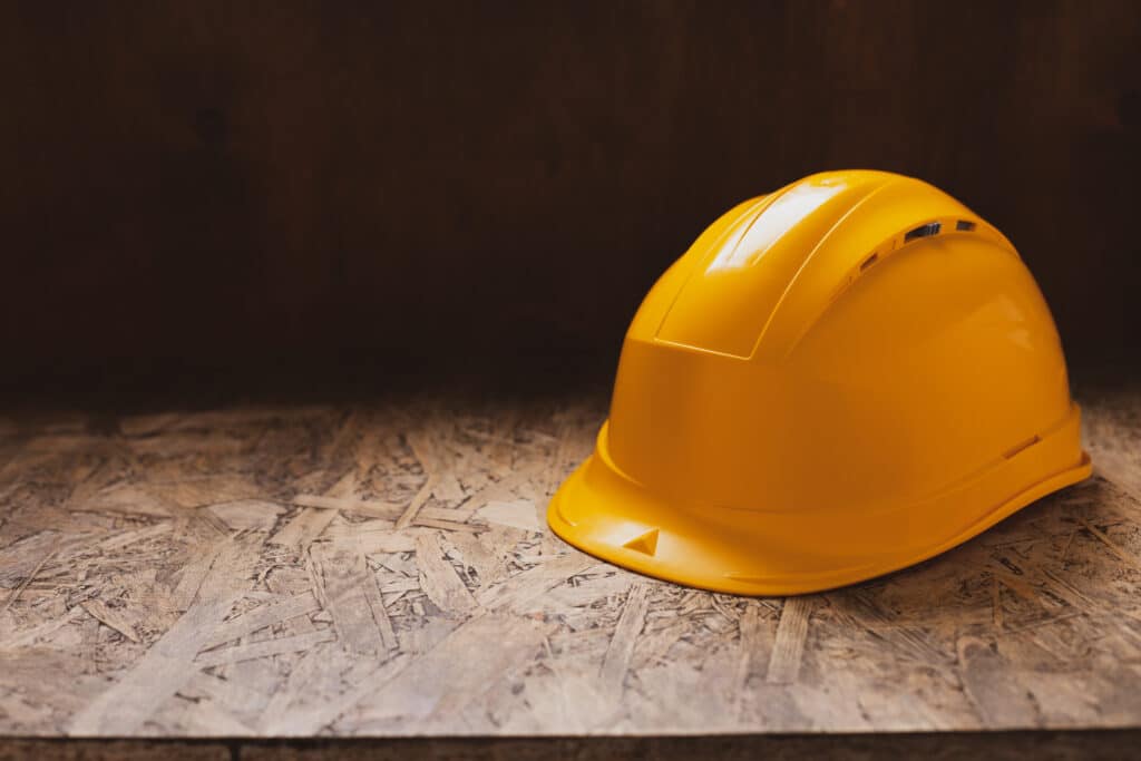 Construction helmet at wooden table background texture. Work cap and concept of renovation
